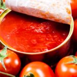 Immagine di una bottiglia di passata di pomodoro con un'etichetta di avvertimento sui rischi per la salute.