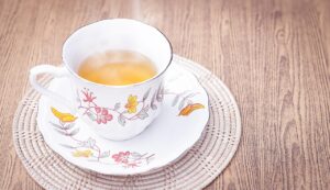 Tazza di tè tiepido fumante su un tavolo, ideale per bruciare grassi addominali al mattino.