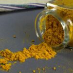 Curcuma in polvere versata su un cucchiaio, simbolo di metabolismo e perdita di peso.