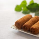 Involtini di pollo farciti, serviti su un piatto decorato con erbe fresche.