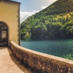 Lago segreto in Piemonte circondato da boschi incantati e riflessi magici nell'acqua.